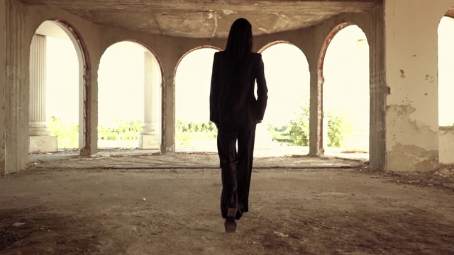 一个不可辨认的黑发女人走在被遗弃的建筑里视频下载