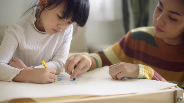可爱的亚洲女孩做家庭作业，在她的母亲的帮助下。视频下载