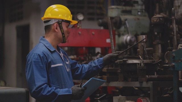 工厂技术人员或工人戴黄色头盔和蓝色制服检查货架上工具的质量和数量视频素材