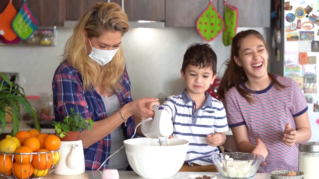 4K妈妈用防护口罩和她的孩子做美味的纸杯蛋糕在家隔离病毒视频下载