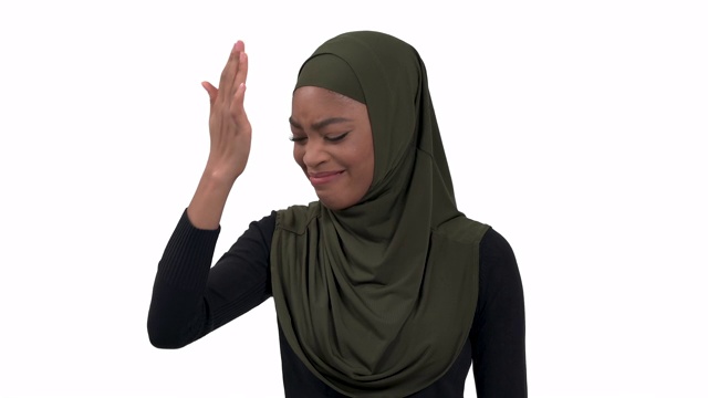 穆斯林黑皮肤女子表达遗憾情绪。模特咬自己的额头。孤立，在白色背景上。人类的情感，肢体语言视频素材