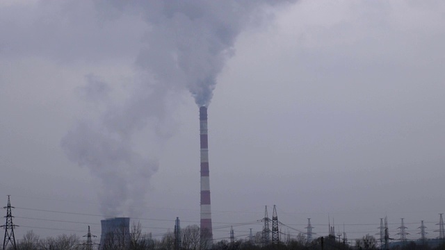 浓重的灰色烟雾从火电厂的烟囱管道中倾泻到大气中。工业工厂烟囱排放的二氧化碳。环境污染和全球变暖。视频素材