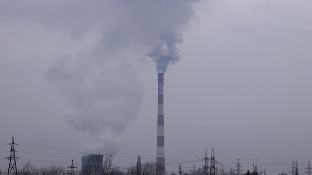 浓重的灰色烟雾从火电厂的烟囱管道中倾泻到大气中。工业工厂烟囱排放的二氧化碳。环境污染和全球变暖。视频素材
