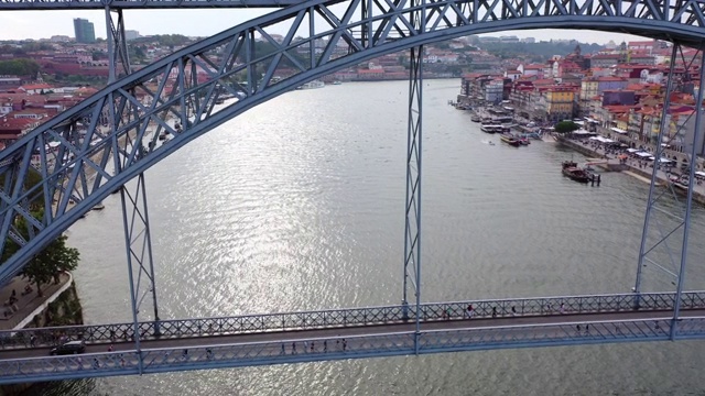 航拍人们在城市河上的桥上行走，无人机在水面上空降落——葡萄牙波尔图视频下载