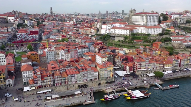 空中倾斜拍摄的游客在城市的建筑物和河流码头上，无人机在天空中飞过城市景观——葡萄牙波尔图视频下载