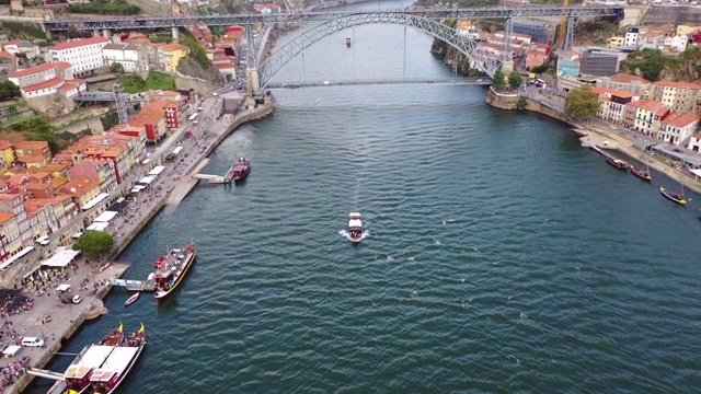 在葡萄牙波尔图，空中倾斜拍摄的是河上的一艘船对着一座著名的大桥，无人机飞过建筑中的船只视频下载