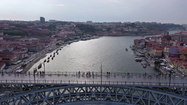 航拍游客在河上的桥梁上的建筑，无人机在多云的天空下向前飞行城市-葡萄牙波尔图视频下载