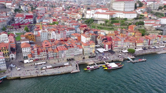 航拍倾斜，游客在码头上的建筑和河流在城市，无人机飞过城市景观的天空-波尔图，葡萄牙视频下载