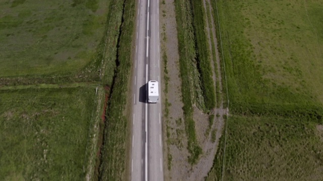 航拍的大篷车行进在风景中的道路上，无人机向前飞行在风景优美的土地中露营车-冰岛西南部，冰岛视频下载