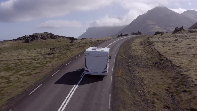 航拍露营车在向山的道路上移动，无人机向前飞行在景观上的大篷车-冰岛西南部，冰岛视频下载