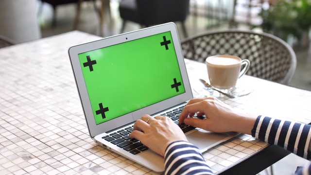 近距离女子使用笔记本电脑与绿色屏幕在咖啡馆视频素材