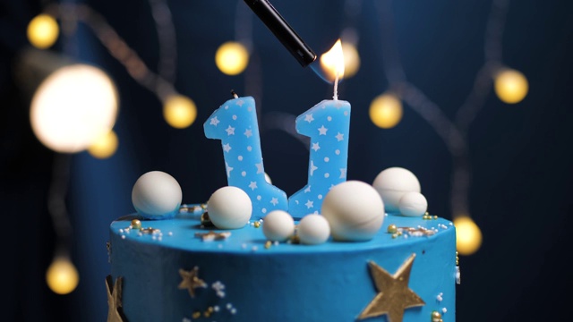 生日蛋糕号11星星天空和月亮概念，蓝色蜡烛是火由打火机然后吹灭。如果需要，在屏幕右侧复制空间。特写和慢动作视频下载