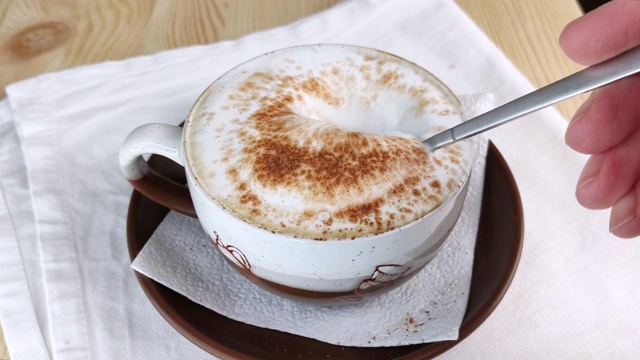 卡布奇诺或拿铁咖啡。用勺子舀牛奶从咖啡中起泡视频下载