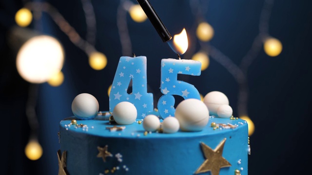 45号生日蛋糕星星天空和月亮概念，蓝色蜡烛是火由打火机然后吹灭。如果需要，在屏幕右侧复制空间。特写和慢动作视频下载