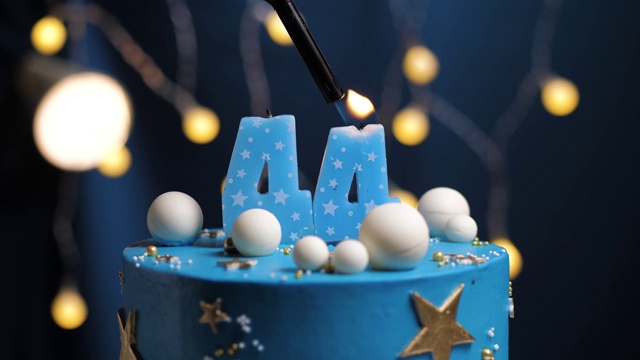 44号生日蛋糕星星天空和月亮概念，蓝色蜡烛是火由打火机然后吹灭。如果需要，在屏幕右侧复制空间。特写和慢动作视频下载