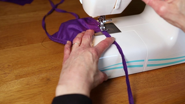 妇女在缝纫机上做口罩视频下载
