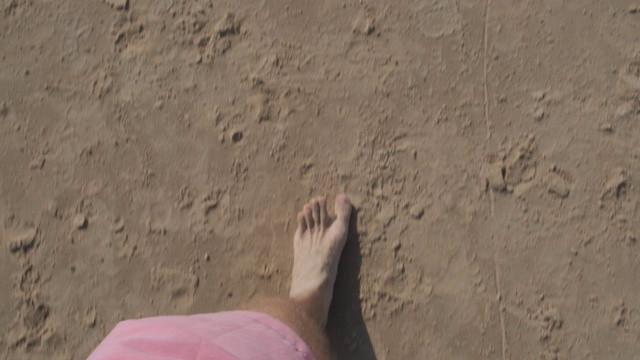 视点运动视频的腿和脚的一个年轻人走在沙滩上视频素材