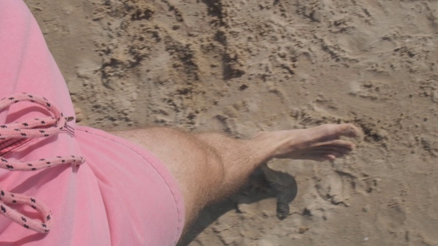视点运动视频的腿和脚的一个年轻人走在沙滩上视频素材