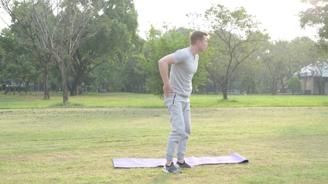 年轻英俊的男子在公园冥想后，滚动瑜伽垫视频下载