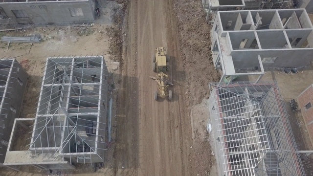 无人机拍摄的是一架平地机在建筑工地工作的画面视频素材