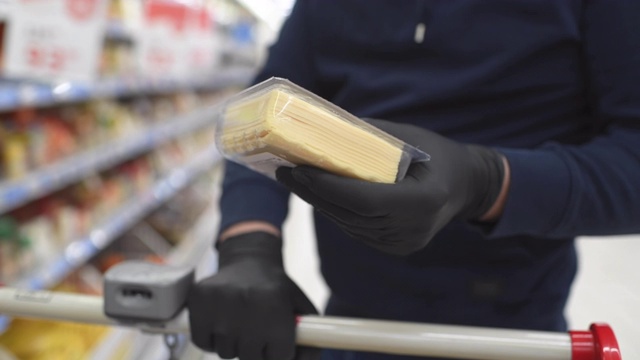 在食品杂货店里，戴着防护手套的男子双手拿着奶酪视频素材