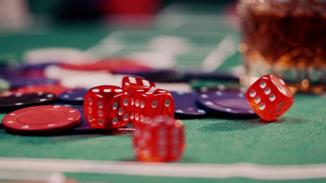 在一堆扑克筹码上滚动红色骰子的特写镜头视频下载