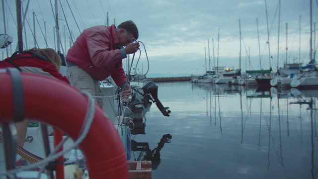 一个六十多岁的船长在他的帆船上工作的慢动作拍摄在普吉特海湾在华盛顿黄昏视频素材