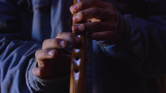 一个十几岁的美国土著男孩在霍根(纳瓦霍小屋)里吹着纳瓦霍长笛。视频下载