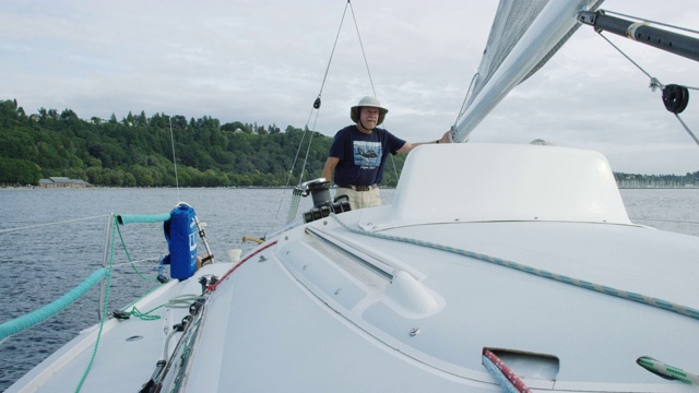 慢动作拍摄的船长检查主帆，而他的小船员在普吉特湾附近的西雅图，华盛顿帆船甲板上工作视频素材