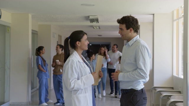 年轻女医生与病人交谈、握手，附带的病人和医生出现在背景中视频素材