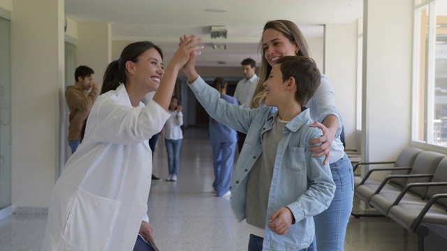快乐的拉丁美洲医生和他妈妈在医院里给一个年轻的病人击掌视频素材