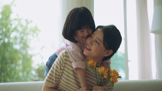 母亲和女儿捧着花，一起在沙发上玩耍视频素材