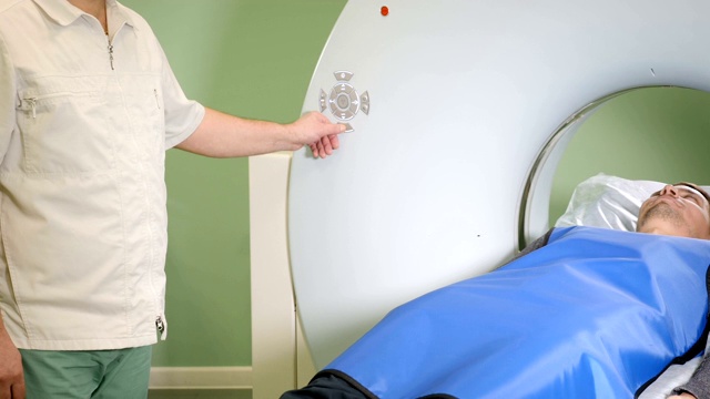 男性病人正在进行ct扫描。医疗设备:诊断门诊用计算机体层摄影机。健康的概念。医生按下CT MRI扫描仪设置按钮。高清视频素材