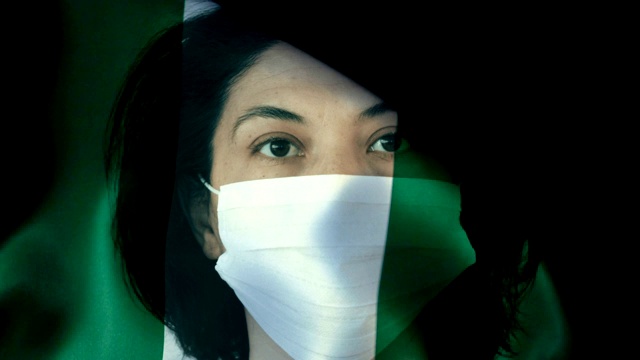 在尼日利亚国旗上戴着面罩的妇女。保护病毒和感染。视频下载