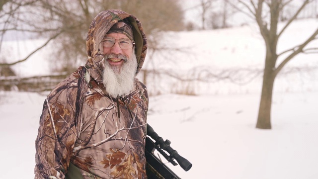 成熟的男人穿着迷彩服在冬天打猎用十字弓。视频下载