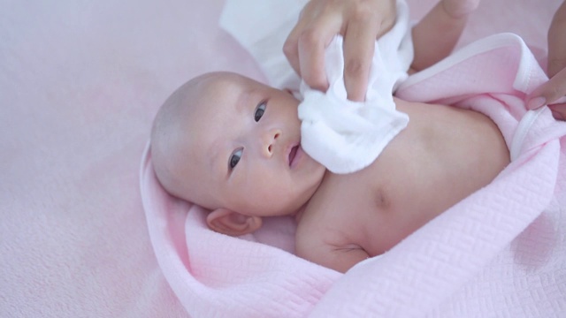 宝宝哭后，用粉红色的毛巾和母亲的手洗澡。视频下载