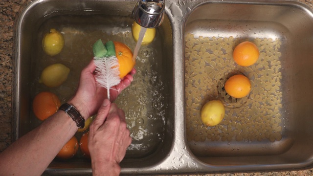 COVID-19男子用头顶MS刷清洁水槽中的柑橘视频素材