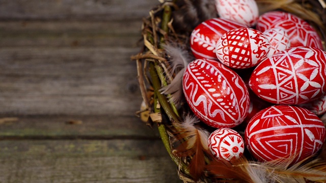 复活节红蛋用民间图案编成鸟巢，以古朴的木头为背景。手加蛋窝。乌克兰传统鸡蛋pisanka和krashanka。视频素材