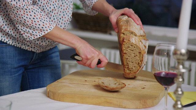 一个女人在餐桌上切面包的特写镜头视频素材