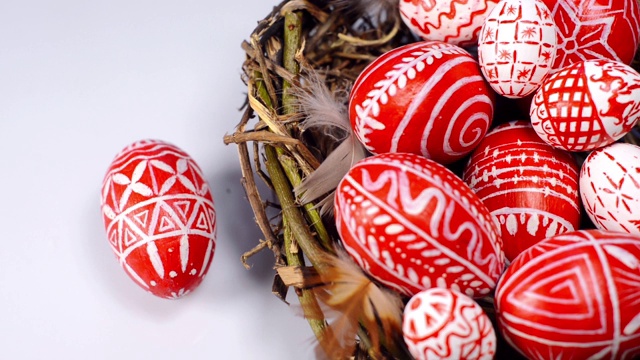 白色背景上的红色乌克兰图案复活节彩蛋。男人的手旋转一个鸡蛋。乌克兰传统鸡蛋pisanka和krashanka。视频素材