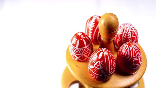 带有乌克兰民间图案的红色复活节彩蛋摆放在木制的蛋架上，蛋架在白色背景的右侧。乌克兰传统鸡蛋pisanka和krashanka。视频素材
