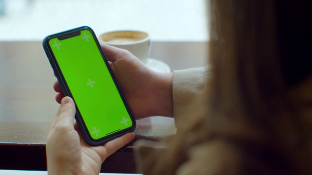 迷人的年轻女子使用她的绿色触摸屏手机在咖啡馆。视频素材