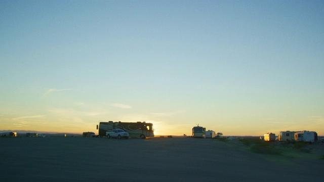 在帝国沙丘国家休闲区附近的尤马，亚利桑那州在一个晴朗的晚上日落和剪影的房车移动的镜头视频下载