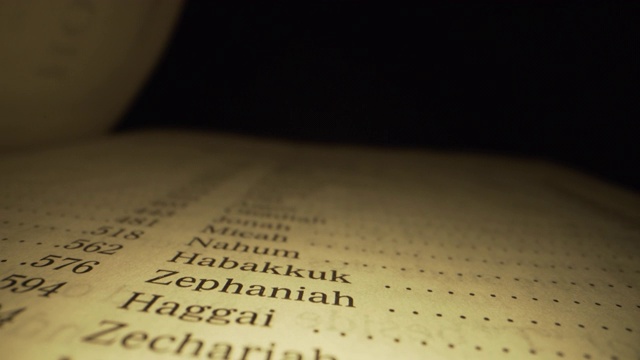 极端微距特写移动滑块拍摄的圣经旧约索引书在国王詹姆斯翻译与红色字母的上帝的话在一个黑暗的背景与独特的照明视频下载