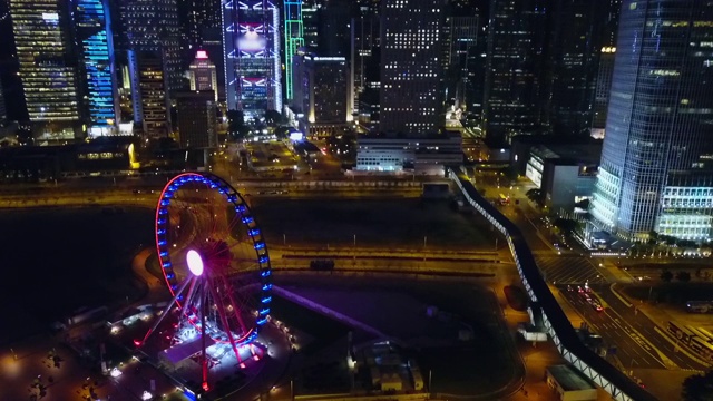 空中倾斜向下拍摄的灯光摩天轮在夜晚的街道上，无人机飞过城市与现代建筑-香港，中国视频素材