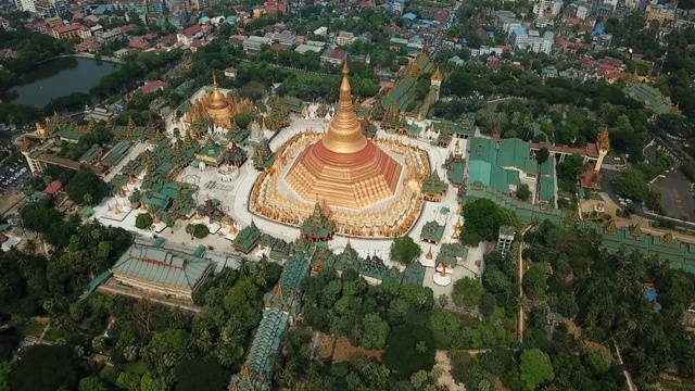 空中拍摄在城市树木中的金色佛塔，无人机飞过寺庙-仰光，缅甸视频下载