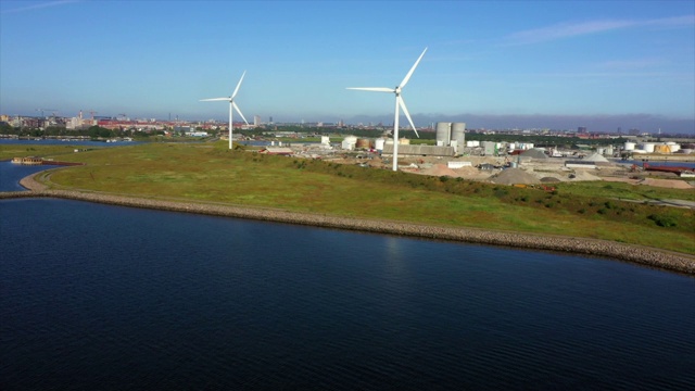 空中平移拍摄的风力涡轮机在城市的海上对着蓝天，无人机飞过海岸线在阳光明媚的一天-哥本哈根，丹麦视频素材
