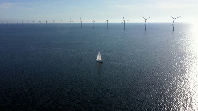 航拍的船航行由风力涡轮机在蓝色的海洋，无人机向前飞向水对天空晴朗的一天-哥本哈根，丹麦视频素材