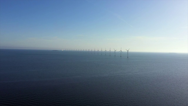 航拍的风力涡轮机在海上划船对蓝色的天空，无人机飞向地平线在晴朗的一天-哥本哈根，丹麦视频素材