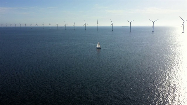 航拍的船航行的风力涡轮机在海上对天空，无人机向前飞向地平线在晴朗的一天-哥本哈根，丹麦视频素材
